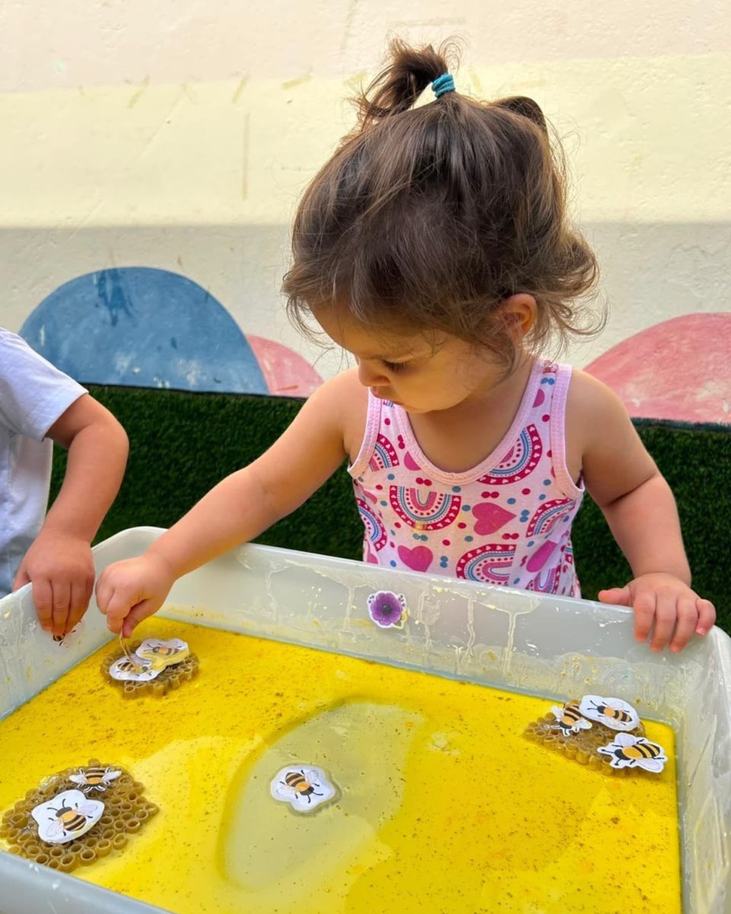 Menina mexendo numa bacia com água amarela